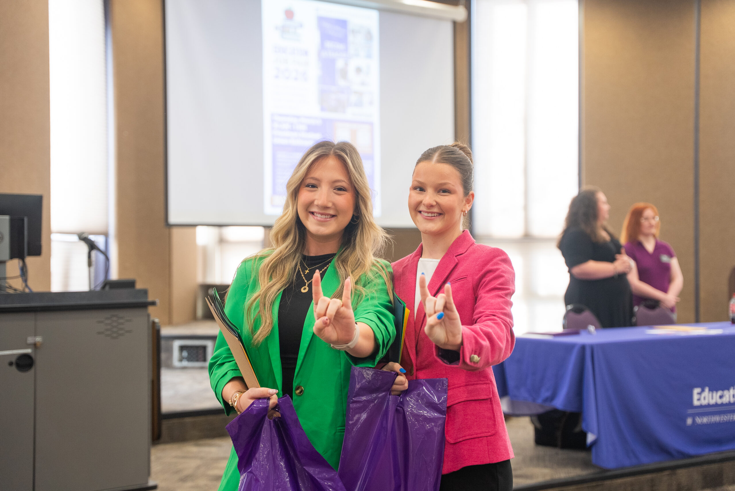 NSU students posed in a pink and green blazers at a career fair