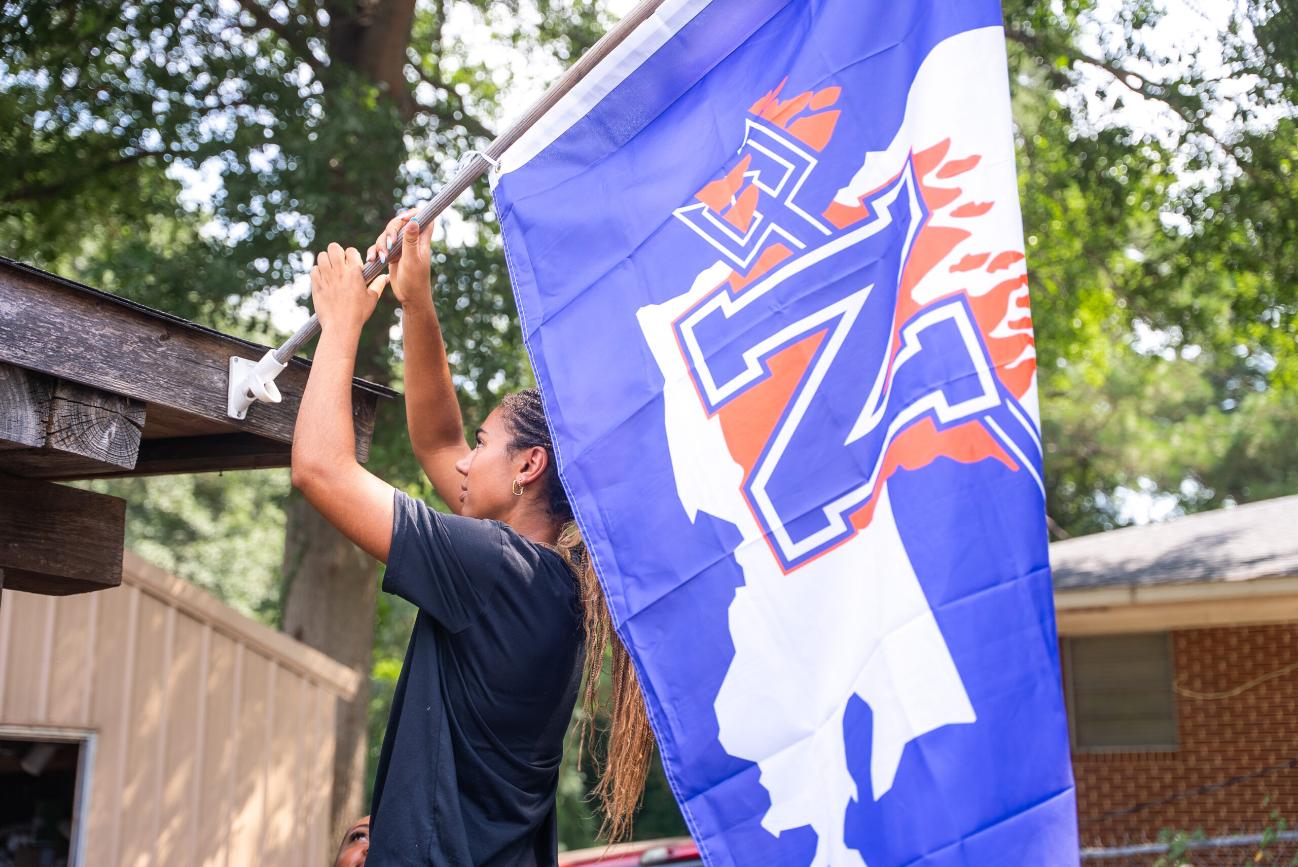 Northwestern State University student Makenna Tryon raises an NSU flag outside a home in Natchitoches.