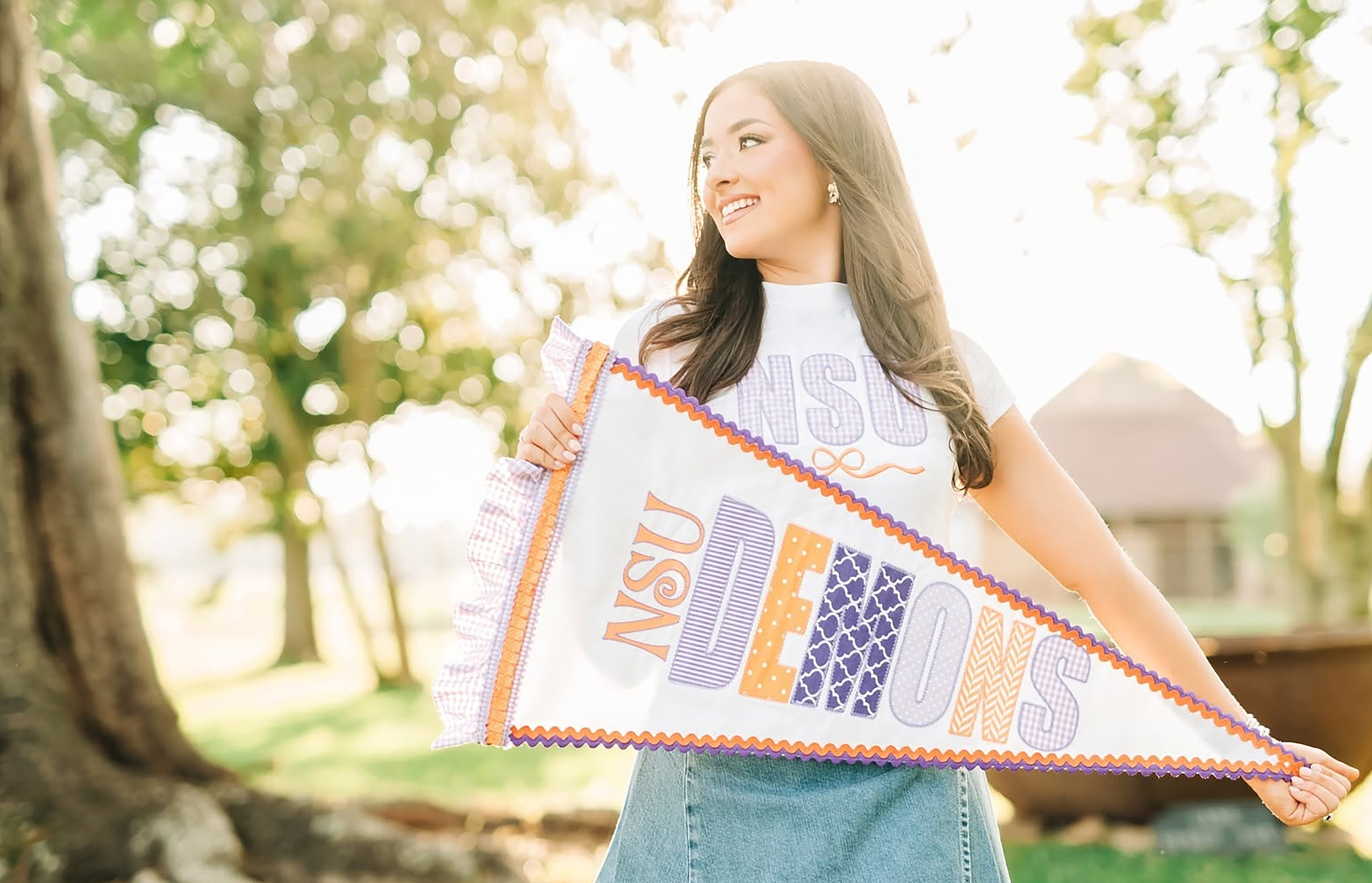 A young woman stands outdoors holding a triangular banner that reads 