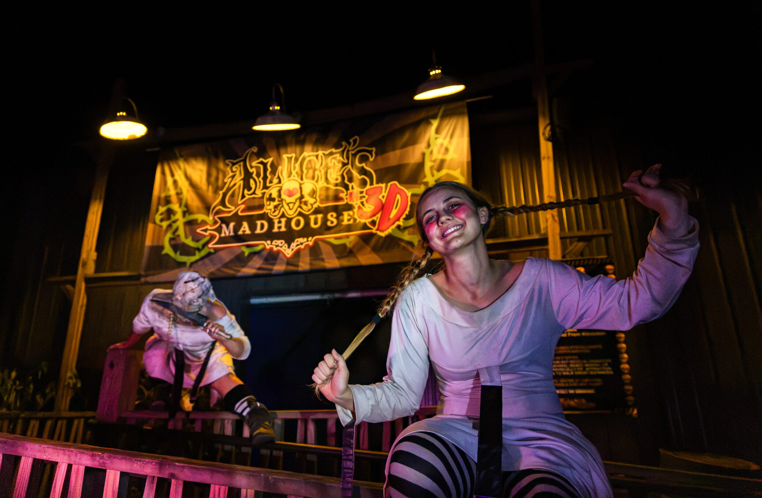 An actor portraying Alice, left, and an NSU student scare actor perform outside Alice's Madhouse in 3D at Dark Woods Haunted Attraction in Natchitoches. The performers' real identities are kept secret as part of the Halloween experience.