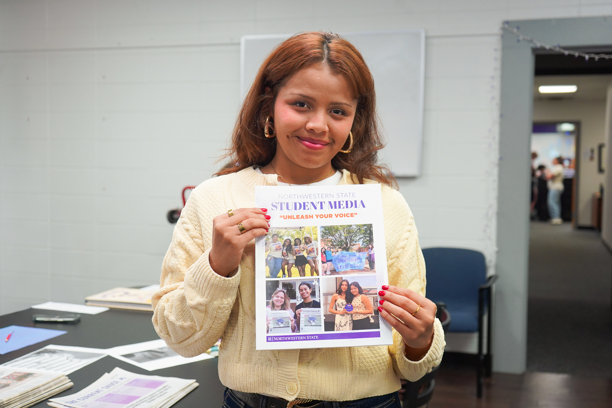 Lluvia Guillot, a multimedia reporter for The Current Sauce, holds a Student Media flyer during the Student Media Open House at Northwestern State University.