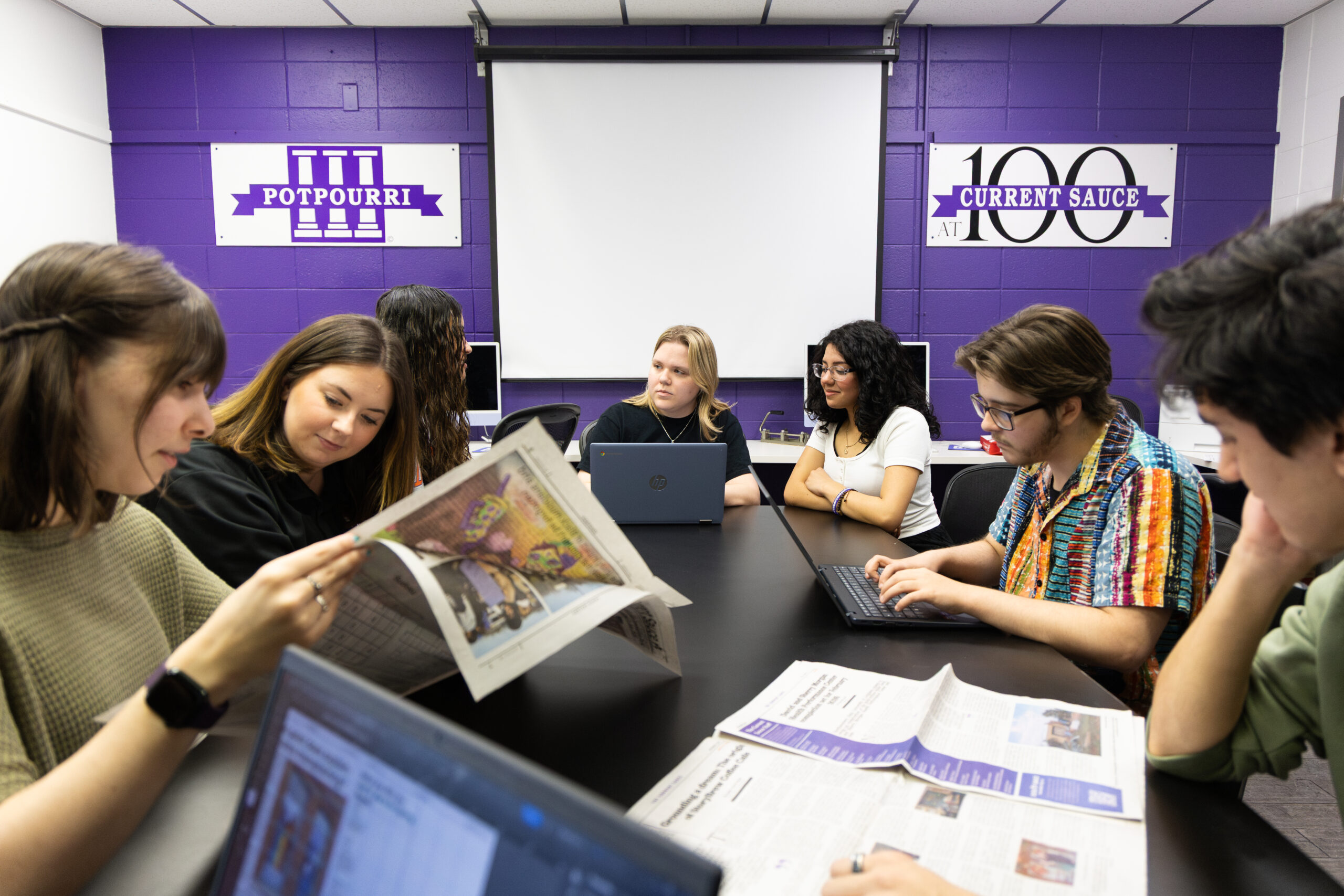 students editing a newspaper together around a table
