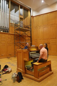 Organmaster JR Neutel, seated; Jeremy Rush, a tonal finisher, and voicer/tuner Carolyn Sargent refined the new digital components of NSU’s pipe organ in Magale Recital Hall.