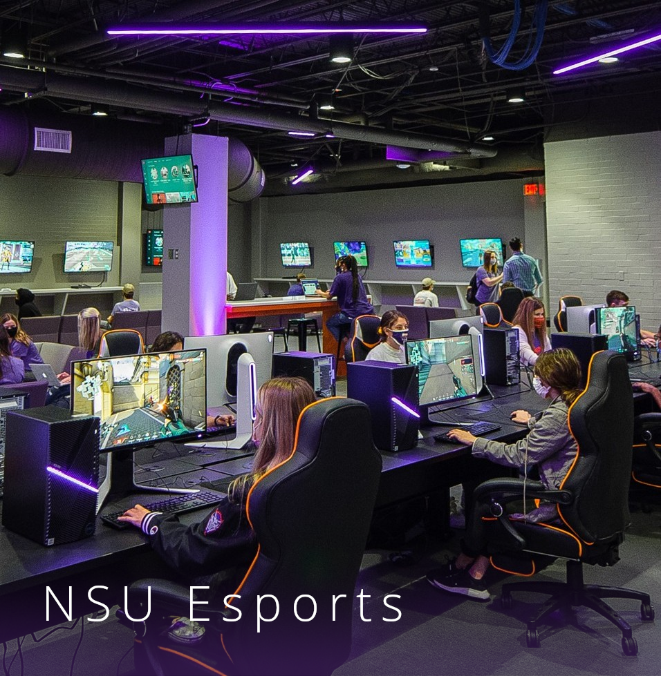 Masked students sit in a purple-lit computer lab engaging in a gaming competition.